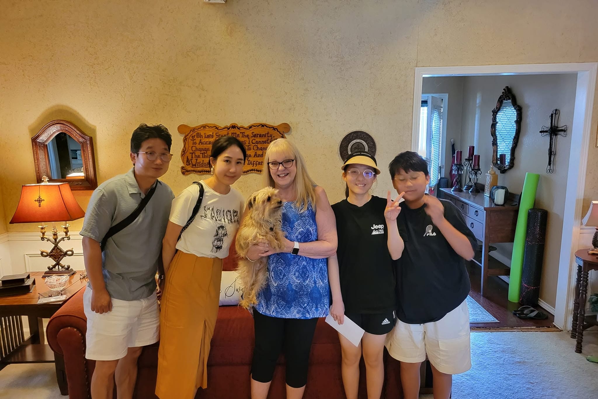 Students and a host family standing together in the front room of a home.